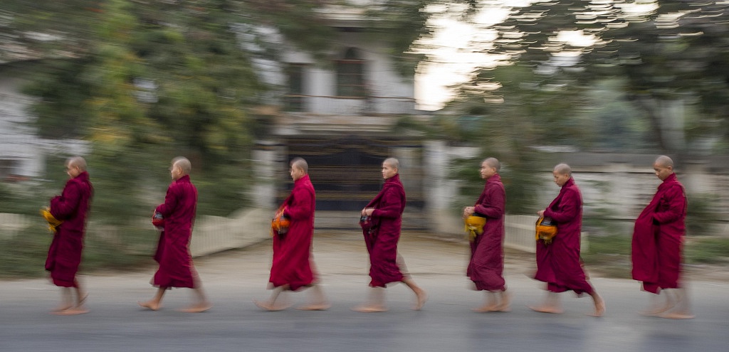 Monks on their early morning arms walk through Mandalay.